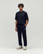 Black jersey t-shirt with small tonal embroidered Psycho Bunny logo on chest, paired with black Mens Gage Patch Jogger featuring a large white outline bunny skull patch on left thigh.