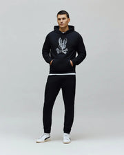 Black relaxed fit french terry hoodie with large white/silver textured Psycho Bunny skull and crossbones chest logo, and Black Mens Barry Joggers with subtle embroidered left thigh logo.