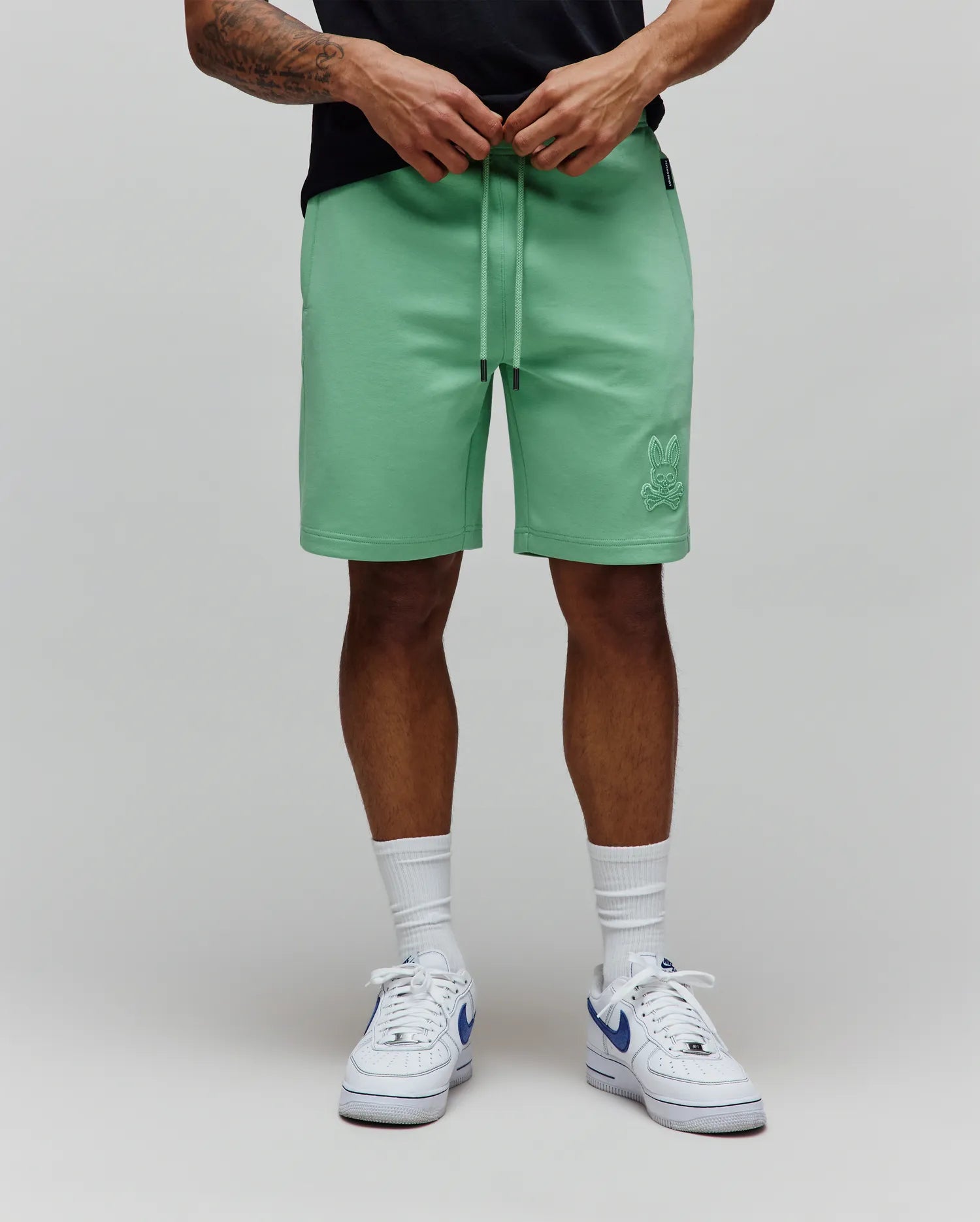 Mint Green Mens Barry Short in relaxed fit jersey fabric, featuring a drawstring waist with black tips and a tonal embroidered Psycho Bunny skull logo on the lower left leg.