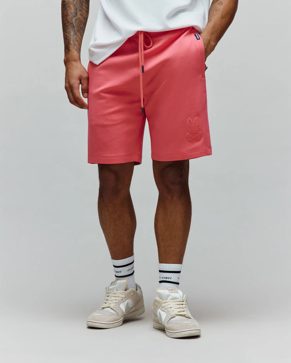 Mens Barry Short, coral french terry shorts with a relaxed fit, featuring a drawstring waist, side pockets, and a tonal embroidered Psycho Bunny skull logo on the right thigh.