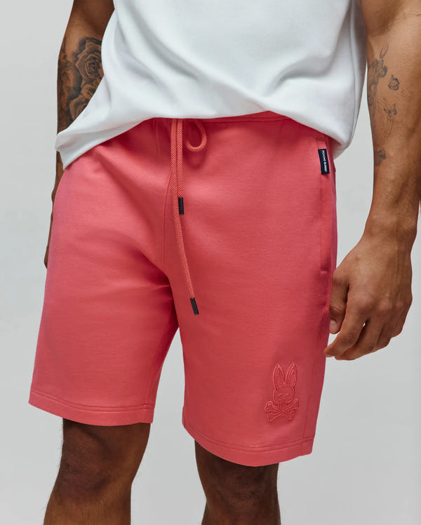 Mens Barry Short, coral relaxed fit French terry shorts with black-tipped drawstring, embroidered Psycho Bunny skull logo on left leg, and side seam brand tag.