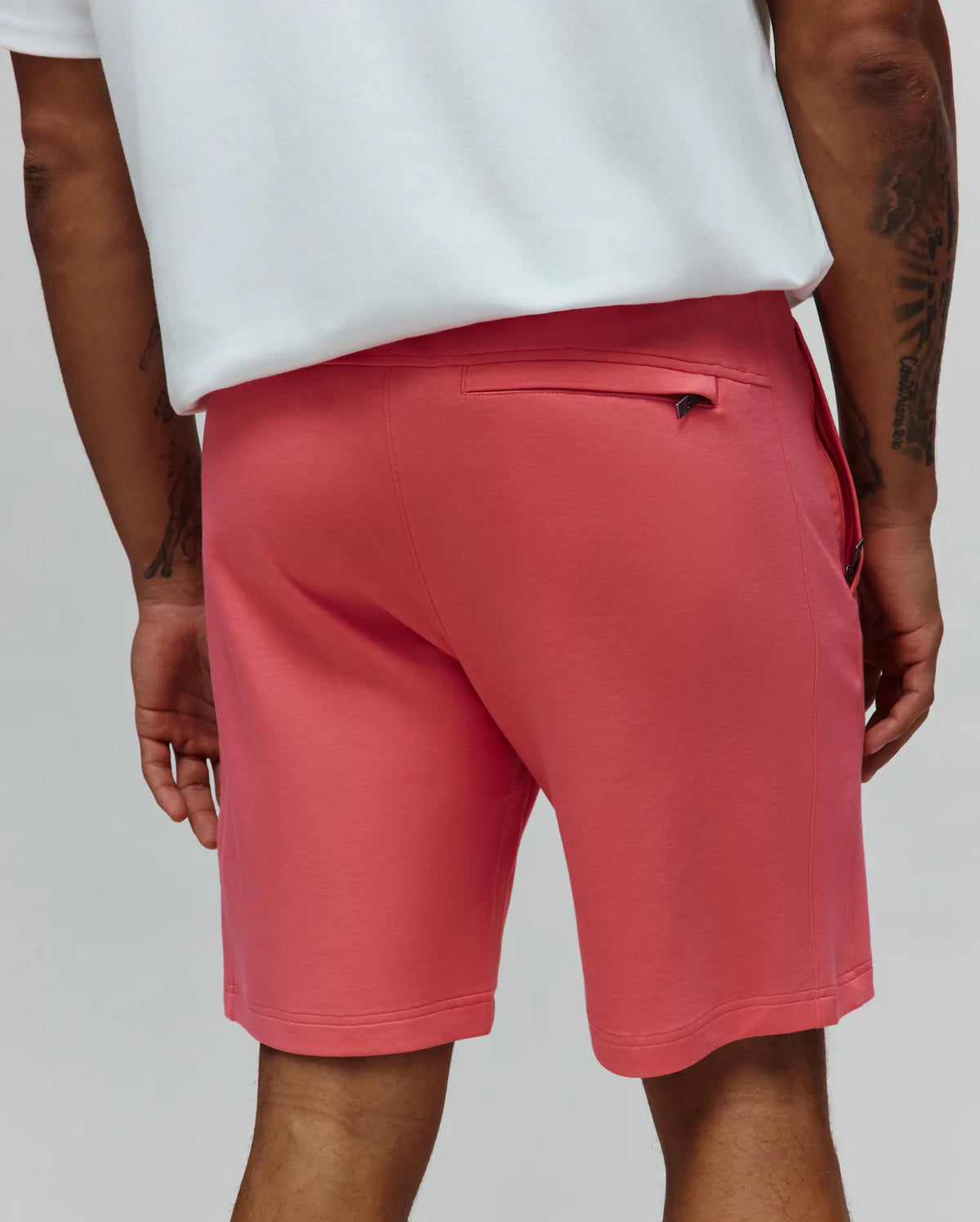 Mens Barry Short in vibrant coral, featuring a smooth jersey knit, classic fit, zippered back pocket with a small Psycho Bunny logo on the metallic pull, and side pockets.