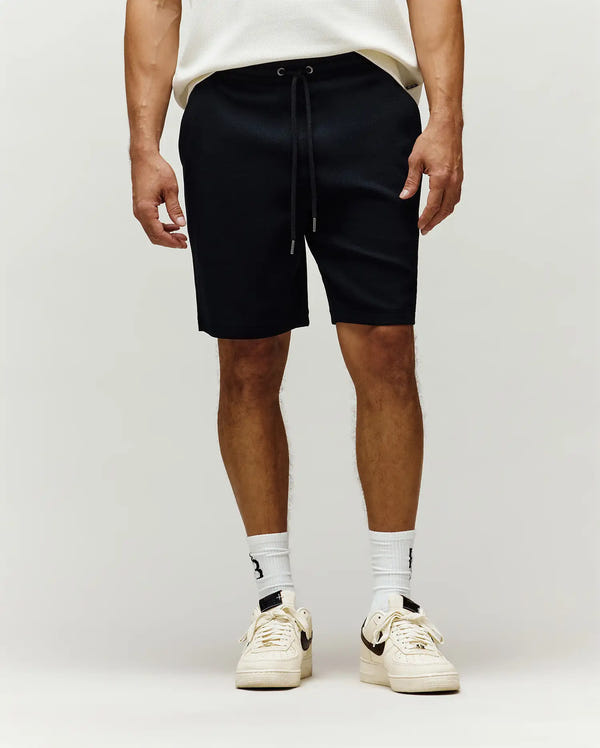 Mens Maxton Waffle Sweatshort in black, featuring a relaxed fit, textured waffle knit fabric, and an adjustable drawstring waist with sleek metal tips.