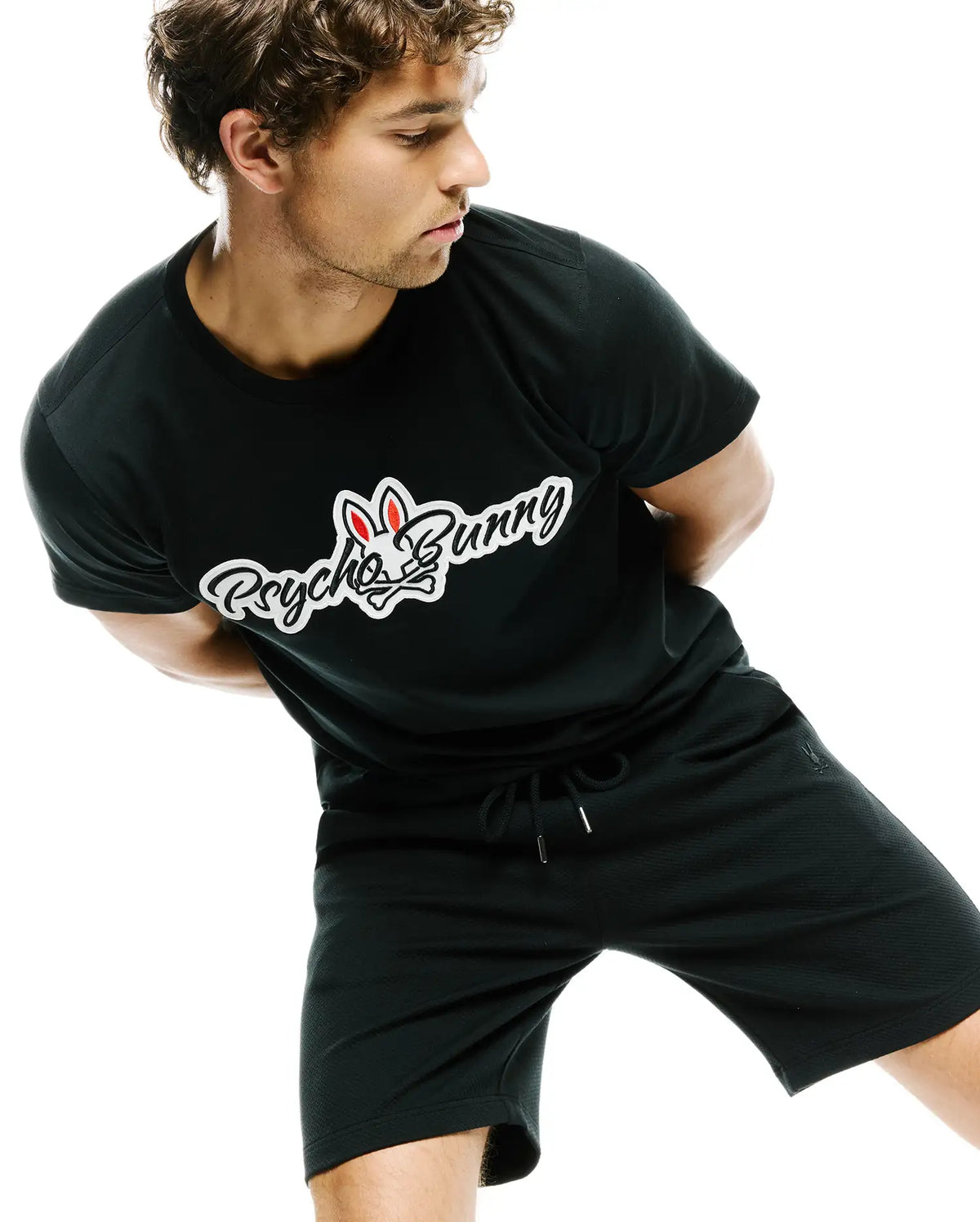 Black classic fit jersey t-shirt with a large white and red Psycho Bunny script logo on the chest, paired with MENS MARC TEXTURED SHORT, black relaxed fit textured knit shorts featuring a drawstring and small bunny skull logo. (2)