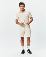 Cream premium textured knit polo with an open collar and small embroidered Psycho Bunny skull logo on the left chest, paired with matching Mens Devon Knit Short with a drawstring waist. (3)