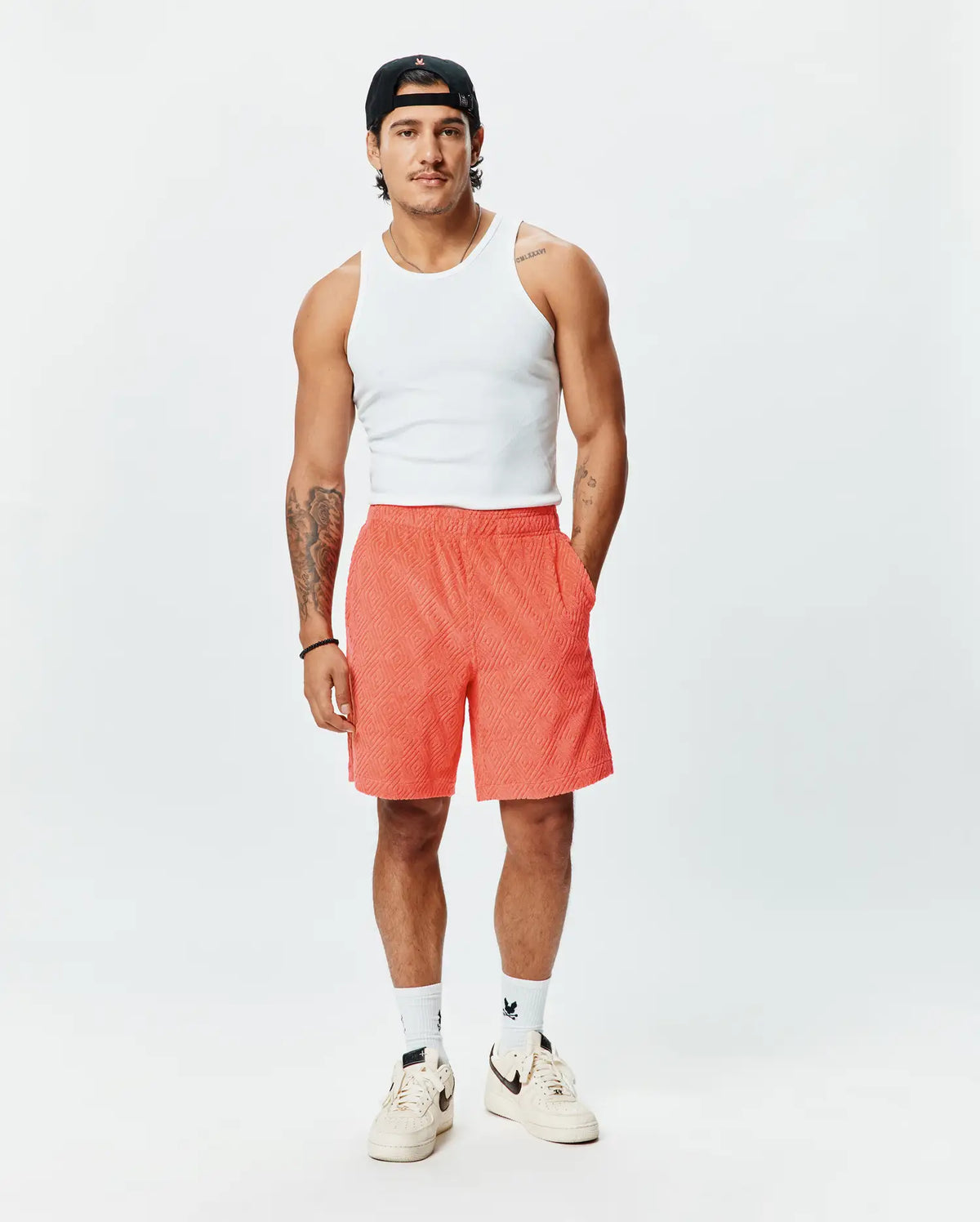 Mens Tristan Short, a premium Psycho Bunny relaxed fit short in vibrant coral, featuring an all-over embossed geometric diamond pattern and practical side pockets. (4)
