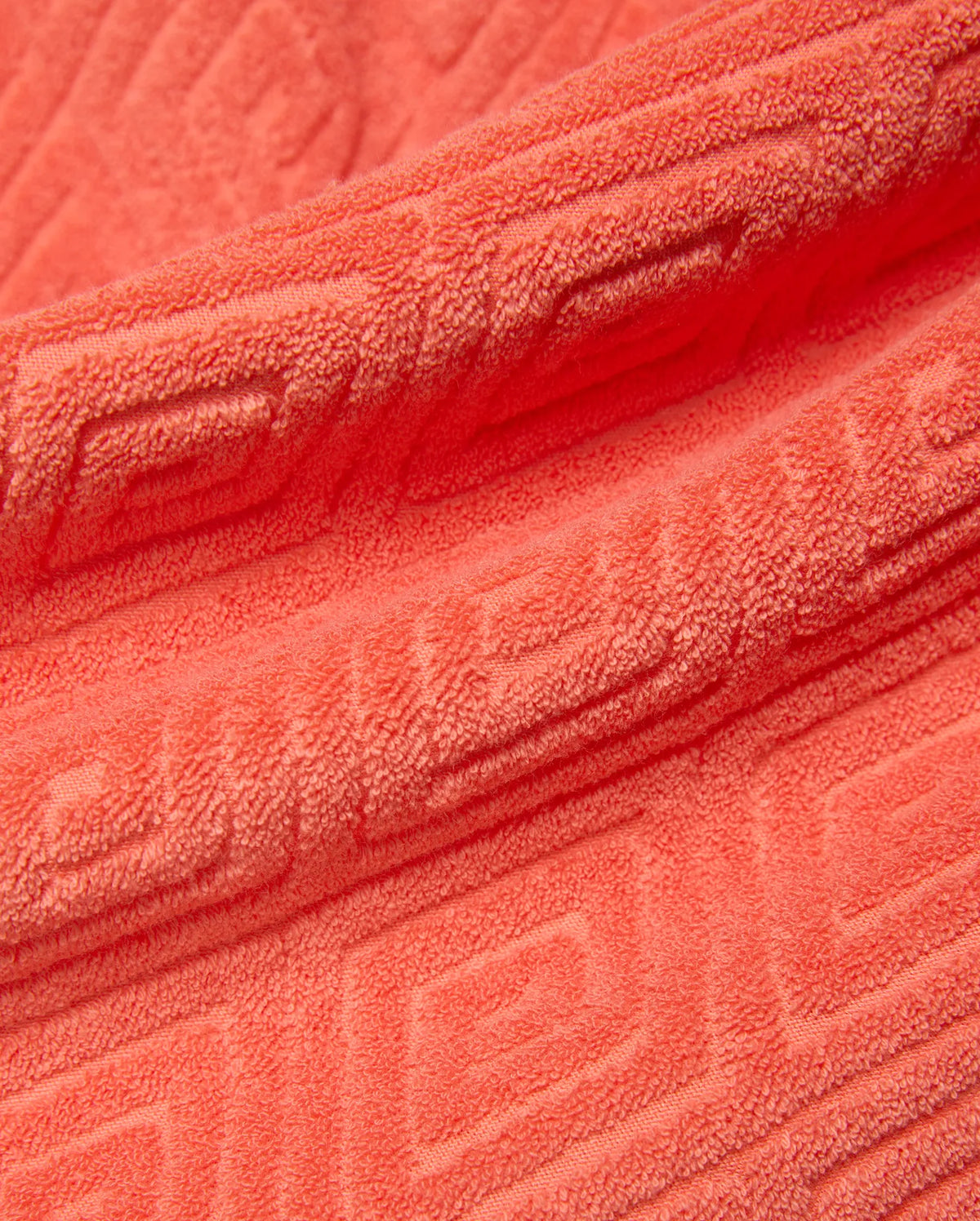 Mens Tristan Short in bold coral terry cloth, featuring a luxurious plush texture and an intricate, all-over embossed geometric maze pattern, reflecting refined streetwear style. (6)
