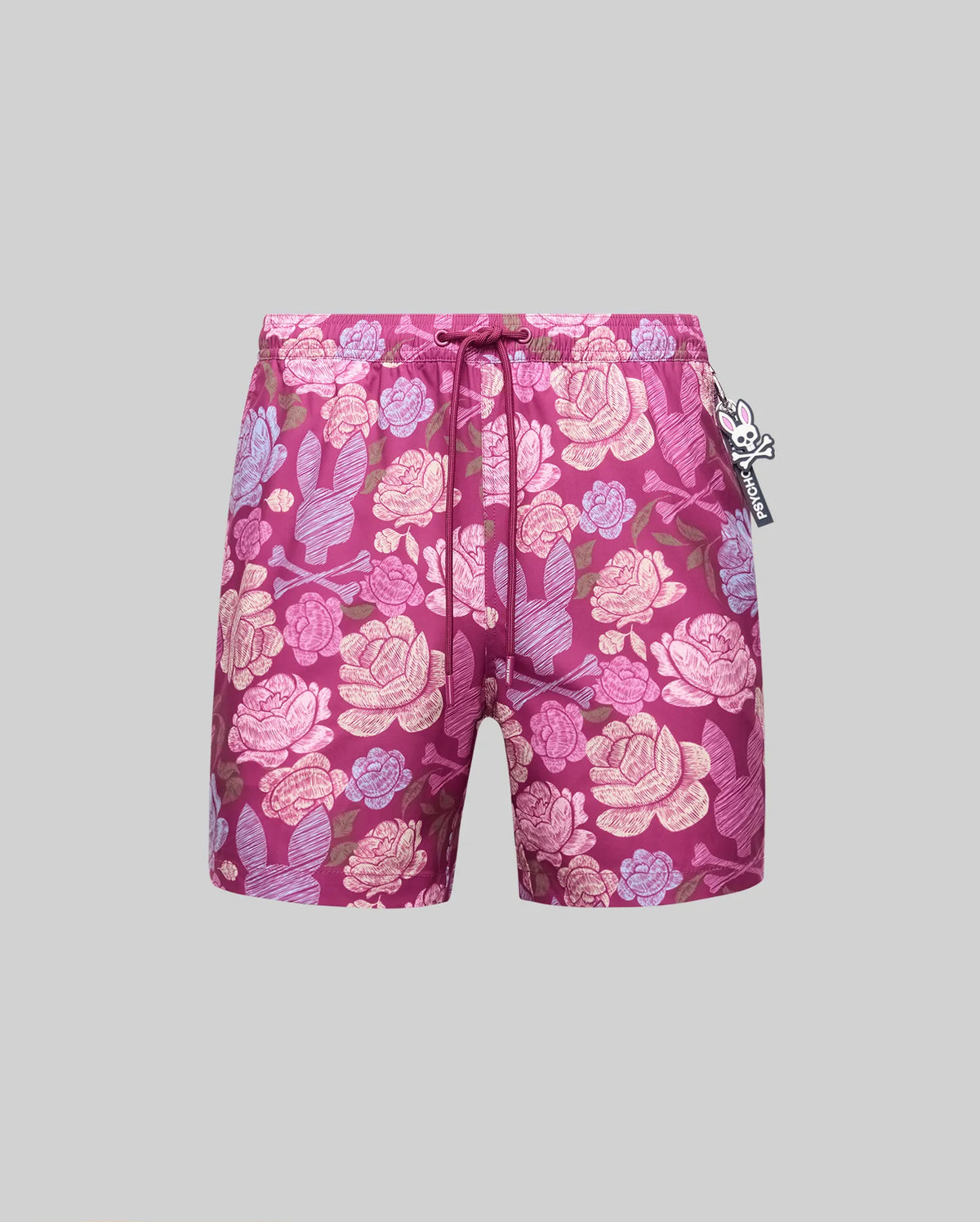 The Psycho Bunny MENS ROWEN SWIM TRUNK - MB1000023 features a magenta floral pink and purple pattern, mesh lining, drawstring waist, and a black-and-white skull tag on the right, shown on a plain gray background.