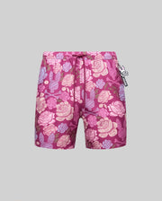 The Psycho Bunny MENS ROWEN SWIM TRUNK - MB1000023 features a magenta floral pink and purple pattern, mesh lining, drawstring waist, and a black-and-white skull tag on the right, shown on a plain gray background.