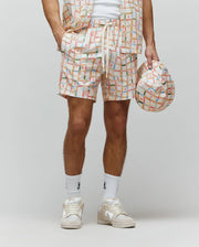 Mens Atlas Swim Trunk in cream with a vibrant multicolor plaid pattern, featuring small repeated Psycho Bunny skull logos and PSYCHO BUNNY text on the drawstring. Relaxed fit, smooth quick-dry fabric.