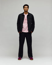 A man faces forward in a Psycho Bunny MENS AVEN KNIT SHACKET (MO1100035), styled over a pink graphic tee, black cargo pants, and dark pink sneakers, effortlessly displaying transitional comfort against a plain light gray background.