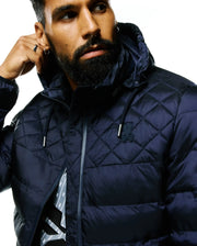 Mens Emerik Hooded Puffer Jacket in navy, featuring a diamond quilted upper, full grey zip, and a small embroidered Psycho Bunny skull logo on the left chest. Shiny puffer fabric, classic fit. (2)