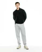 Mens Joaquin Mix Media Reversible Bomber in black, featuring large tonal Psycho Bunny lettering across the chest, paired with light grey relaxed fit french terry sweatpants with a small embroidered bunny skull logo on the left thigh. (5)