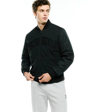 Mens Joaquin Mix Media Reversible Bomber in dark green, featuring a classic fit, full zip, ribbed black collar, cuffs, and hem, with a large arched black PSYCHO BUNNY text logo across the chest and contrasting sleeve fabric. (1)