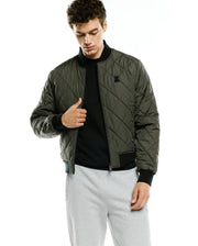 Mens Joaquin Mix Media Reversible Bomber in olive green with diamond quilting, black ribbed collar, cuffs, and hem, featuring a small black embroidered Psycho Bunny skull logo on the left chest. (4)