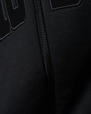 Mens Joaquin Mix Media Reversible Bomber in black, showcasing large raised black letters with a subtle grey outline on a smooth knit fabric, alongside a black front zipper. (3)