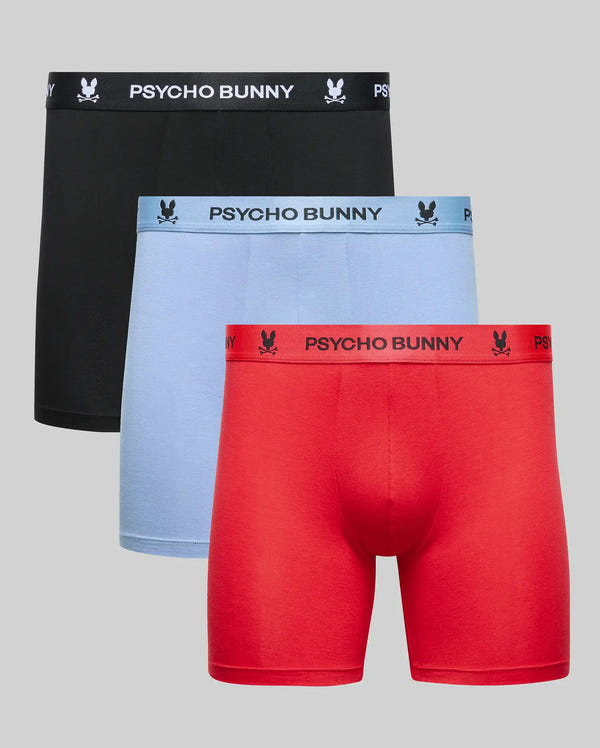 The Psycho Bunny MENS 3 PACK BOXER BRIEF (MO1400006) includes three cotton-modal pairs in black, light blue, and red, each with logo and brand name on the waistband, shown against a light gray background.