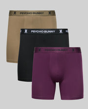 The Psycho Bunny MENS 3 PACK BOXER BRIEF (MO1400008) includes tan, black, and purple pairs crafted from soft cotton-modal with a branded waistband, shown against a light gray background.