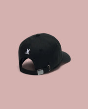 The MENS ARCHIVE BASEBALL CAP (MO1500002) by Psycho Bunny is shown from the back in black cotton, featuring a small white embroidered Bunny logo above its adjustable strap, set against a plain light pink background.
