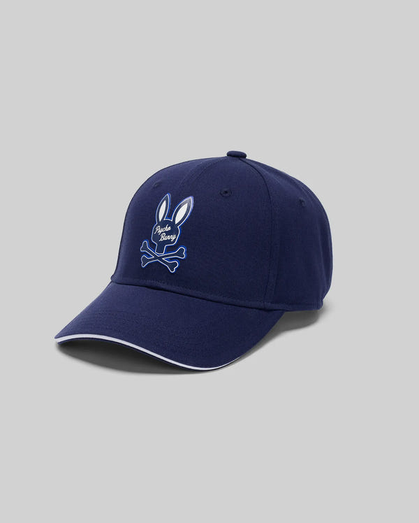 The Psycho Bunny MENS DEREK BASEBALL CAP (MO1500009) is crafted from premium navy blue cotton and features a bold white embroidered bunny above crossed bones, shown against a plain light gray background.