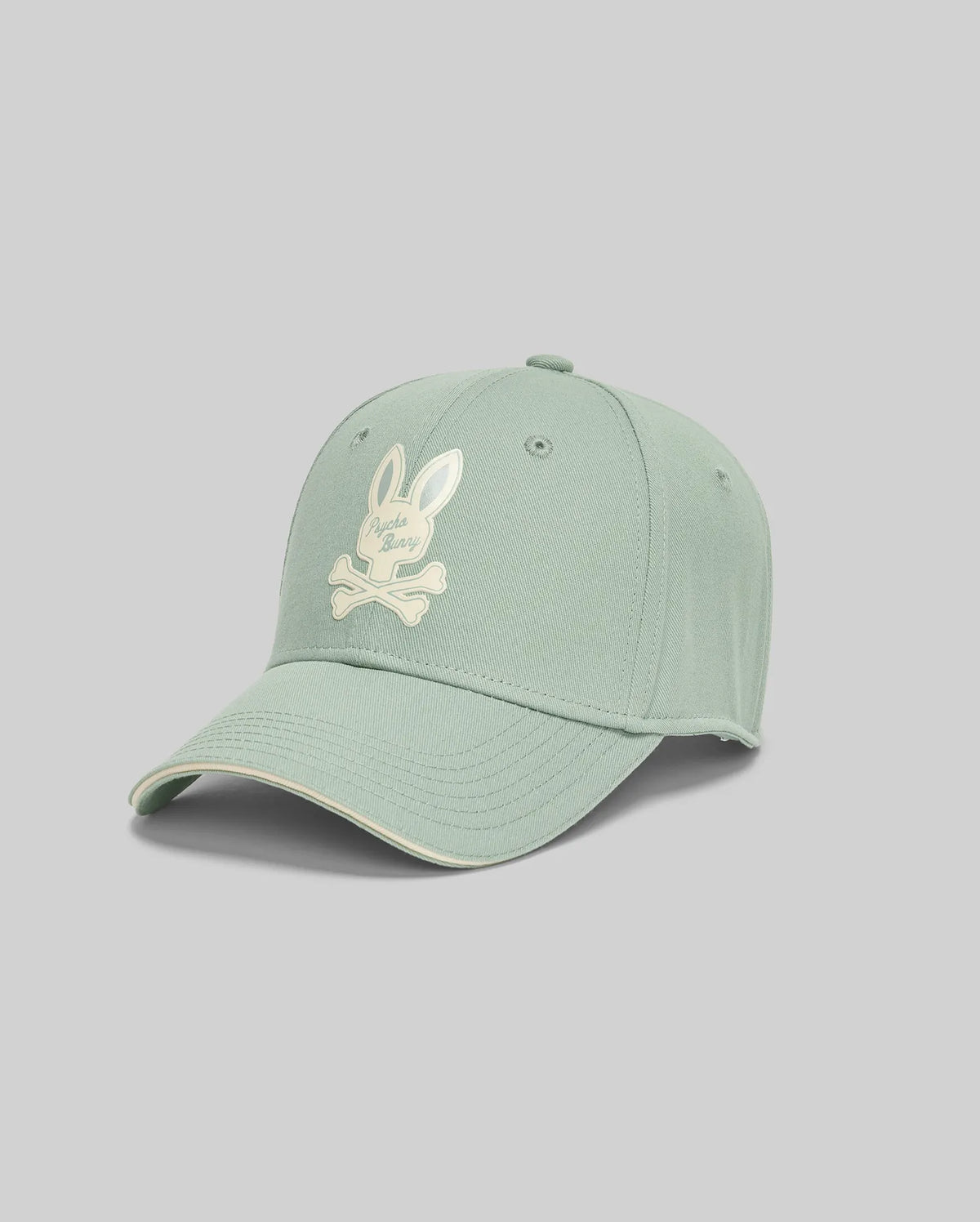 The Psycho Bunny MENS DEREK BASEBALL CAP - MO1500009 is a bold light green cotton cap with a white bunny skull and crossbones logo on the front, shown against a plain light gray background.