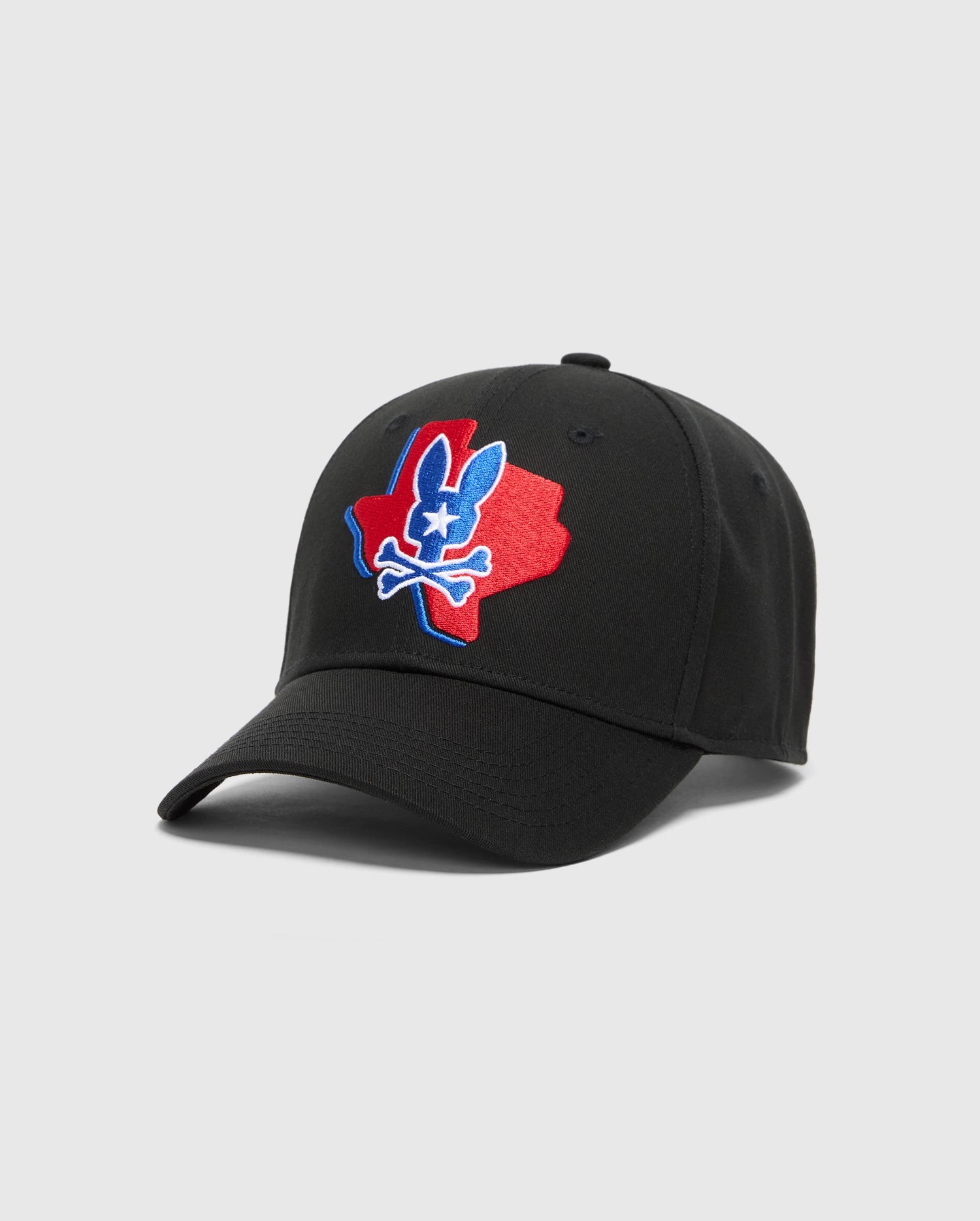 The Psycho Bunny Men's Texas Baseball Cap (MO1500014) is crafted from woven cotton with a colorful embroidered Texas silhouette and bunny skull logo in red, white, and blue. It features a curved brim and an adjustable back strap.