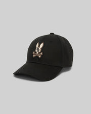 The Psycho Bunny MENS WADE BASEBALL CAP (MO1500039) is a black cotton twill hat with an embroidered Bunny and crossed bones on the front, an adjustable backstrap, shown against a plain gray background.