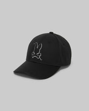 The Psycho Bunny MENS CYRUS BASEBALL CAP - MO1500045 is a black cap with a curved brim, featuring a white embroidered rabbit head and crossbones on the front. The background is plain light gray.