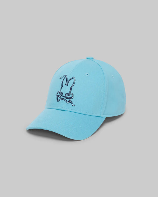 The Psycho Bunny MENS CYRUS BASEBALL CAP (MO1500045) features a light blue design with a curved brim and a dark blue embroidered bunny head with crossed bones on the front, shown against a plain gray background.