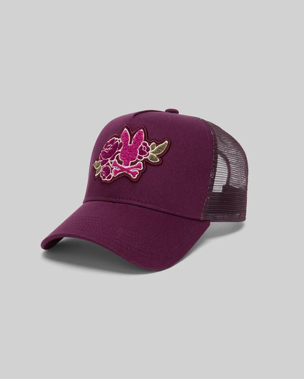 The Psycho Bunny MENS AUGUSTE TRUCKER CAP - MO1500050 is a maroon mesh hat with an embroidered pink and green floral front and adjustable snapback, shown against a plain gray background.