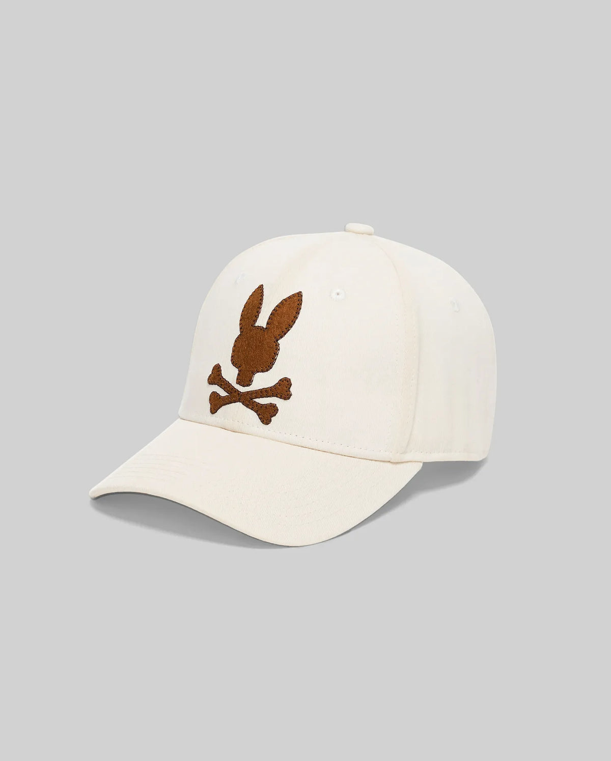 Mens Gage Felted Baseball Cap in cream, featuring a large, central brown felted Psycho Bunny skull logo embroidered on the front.