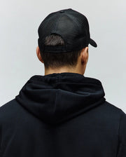 Black Mens Ara Trucker Cap featuring a breathable mesh back and adjustable snap closure, worn with a relaxed fit black Psycho Bunny hoodie crafted from soft jersey fabric.