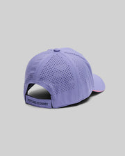 The MENS OFFICIAL US OPEN AVERY NET SPORT CAP (MO1500086) by Psycho Bunny, shown against a gray background, features lavender color, ventilated perforations, and an adjustable strap with a branded label for a breathable sport cap style.
