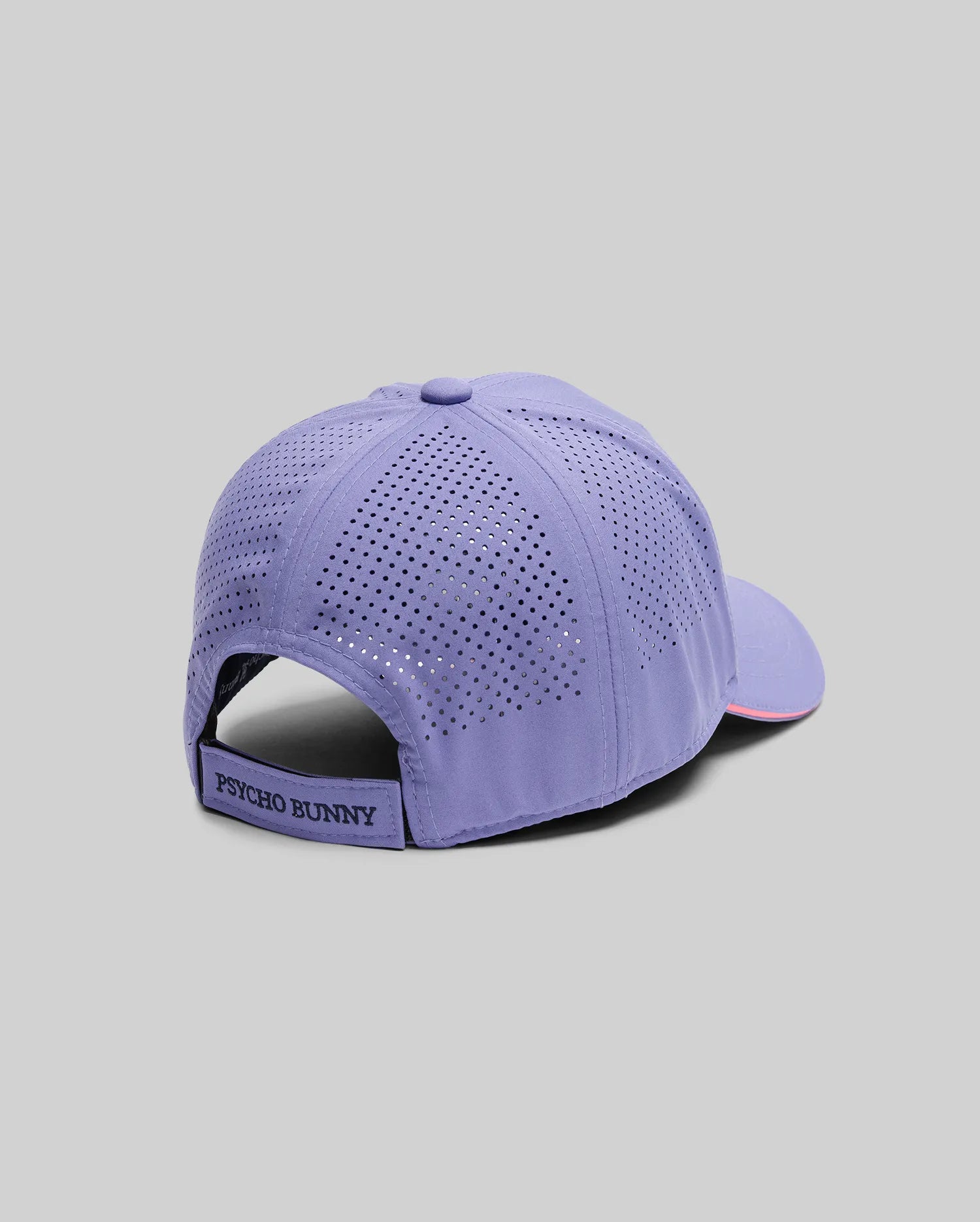 The MENS OFFICIAL US OPEN AVERY NET SPORT CAP (MO1500086) by Psycho Bunny, shown against a gray background, features lavender color, ventilated perforations, and an adjustable strap with a branded label for a breathable sport cap style.
