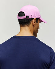 Pink Jimmy Baseball Cap with a small Psycho Bunny skull logo on the back buckle, paired with a classic fit navy blue jersey knit crew neck t-shirt.