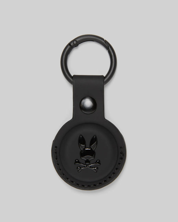 The Psycho Bunny MENS AIR TAG HOLDER - MO1700017 is a round, black leather holder with an embossed bunny logo, snap button, and metal keyring—ideal as a stylish luggage tag.