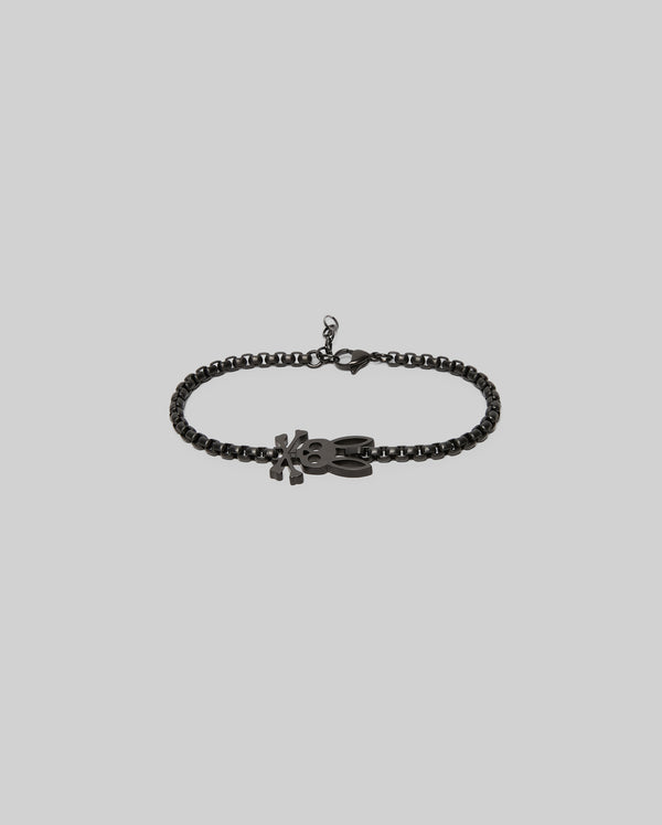 The Psycho Bunny MENS BUNNY BRACELET - MO1700018 features a black chain, a lobster clasp, and an "XO"-shaped pendant for timeless style, shown against a light gray background.