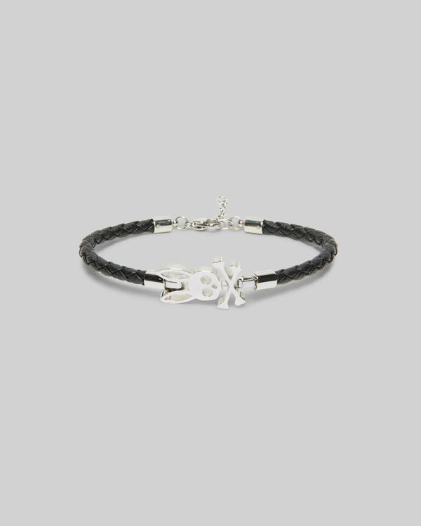 The Psycho Bunny MENS BUNNY LEATHER BRACELET - MO1700024 features black braided leather with a silver-tone rabbit and "X" charm, ideal for daily wear and shown on a plain light grey background.