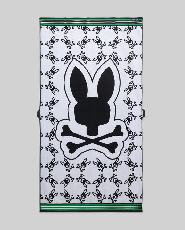 Mens All Over Bunny Towel in white terry cloth, featuring a large central black Psycho Bunny skull logo, an all-over repeating smaller black bunny skull pattern, and green and black striped borders.