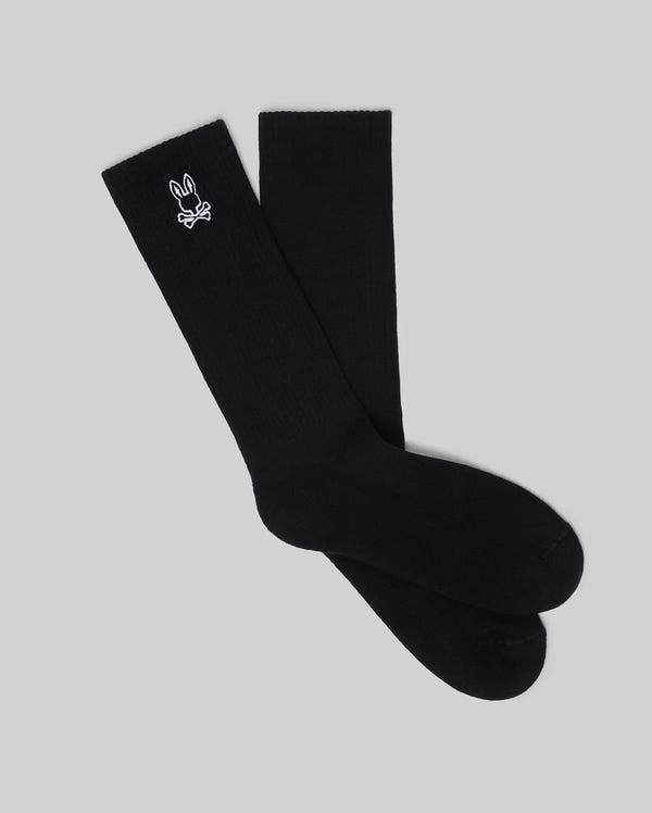 The Psycho Bunny MENS NEW CLASSIC SPORT SOCK - MO2200001 is a black, calf-high crew sock in soft Pima cotton, accented with a small white bunny and crossed bones logo near the top, shown on a plain grey background.