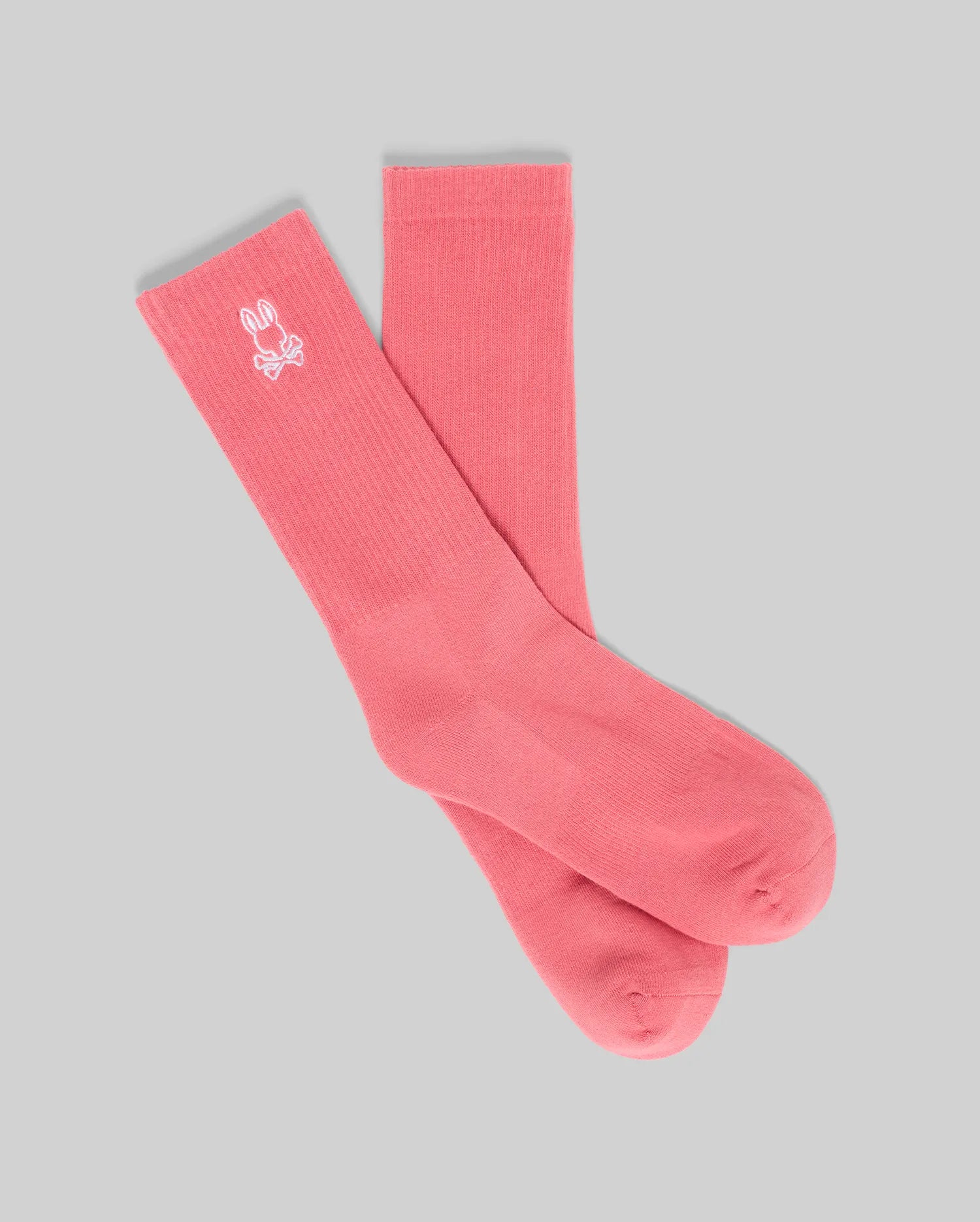 A pair of Psycho Bunny MENS NEW CLASSIC SPORT SOCK - MO2200001 in pink Pima cotton, shown on a light gray background, features a small white embroidered logo near the top for a comfortable, classic look.