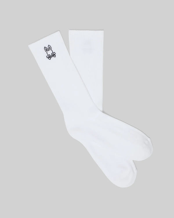 The Psycho Bunny MENS NEW CLASSIC SPORT SOCK - MO2200001 is a white Pima cotton crew sock with a small black cartoon bunny and crossbones embroidered near the top, shown on a light gray background for comfort.