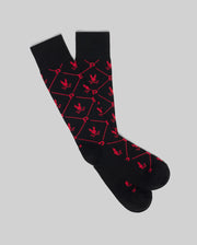 The Psycho Bunny MENS 2 PACK DRESS SOCK - MO2200005 features black knee-high socks with a red hexagonal pattern, "P" designs, and small eagle icons, shown on a light gray background.