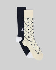 The Psycho Bunny MENS 2 PACK DRESS SOCK - MO2200005 features one solid black sock with a white skull and crossbones, and a cream sock with black geometric patterns, skulls, and “P”, both in soft Pima cotton with white toes and heels.