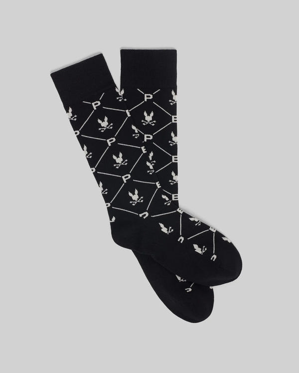 Psycho Bunny’s MEN'S NEW ALL OVER DRESS SOCK (MO2200007) in black is crafted from soft Pima cotton with white geometric motifs—crossed polo mallets, horse and rider, and "P" details. Ideal for formalwear; shown laid flat on a light grey background.