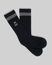 The Psycho Bunny MENS TEXTURED STITCH SPORT SOCK (MO2200017) is a black sock with gray stripes near the top and a white bunny logo on the side, featuring a textured stitch pattern. Displayed on a plain gray background.