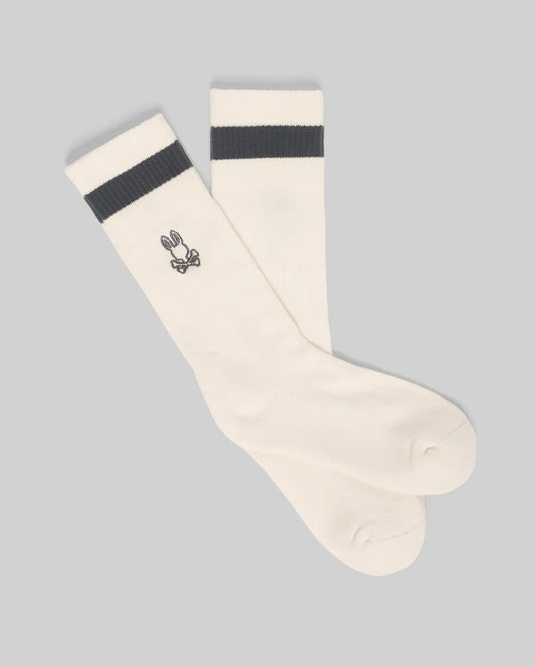 The Psycho Bunny MENS TEXTURED STITCH SPORT SOCK (MO2200017) is a white men's crew sock with a dark gray top stripe and an embroidered cartoon bunny face on the side, shown on a plain gray background.