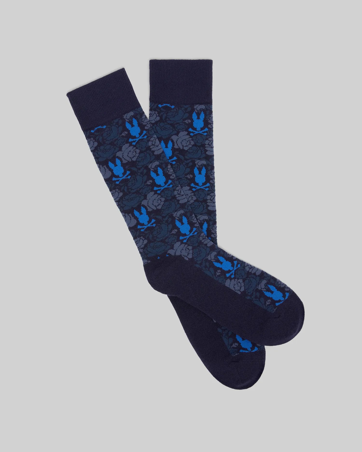 Add a playful touch to your formal wear with Psycho Bunny's MENS FLORAL BUNNY DRESS SOCK (MO2200021), featuring dark blue jacquard knit, floral patterns, and blue rabbit silhouettes.