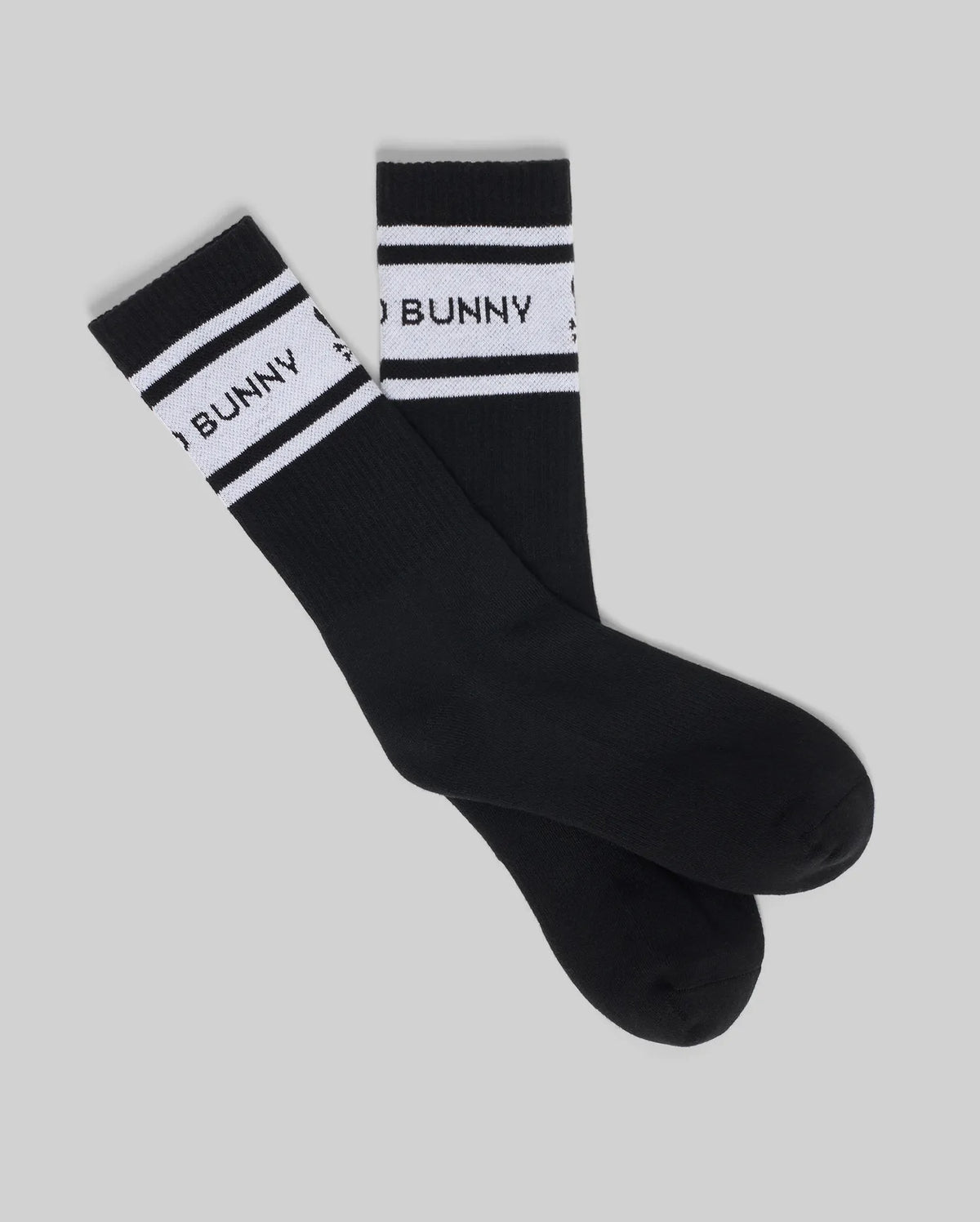 The Psycho Bunny MENS 2 PACK SPORT SOCK (MO2200036) features black cotton sport socks with white stripes and partial "BUNNY" text near the top, shown on a light gray background.