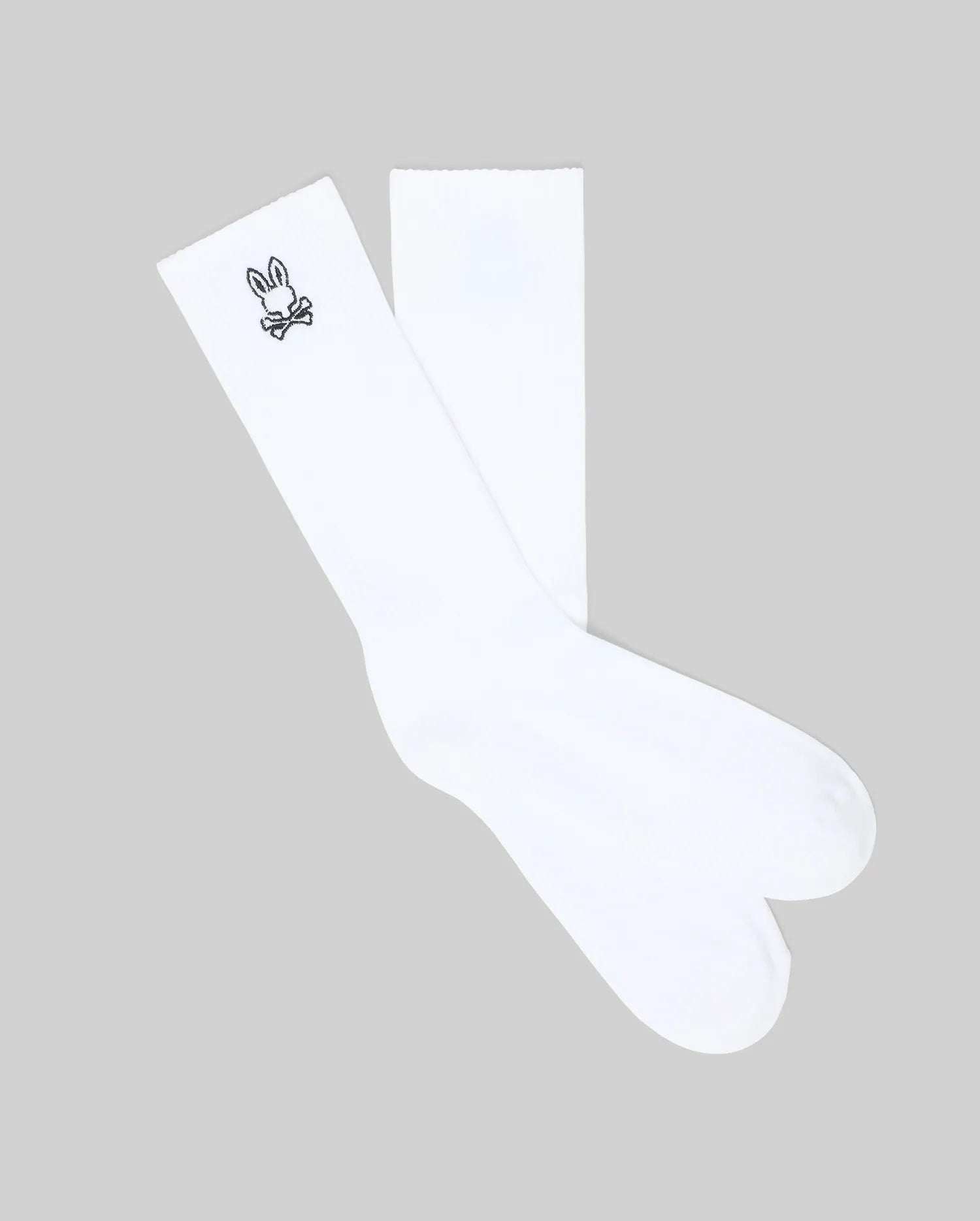 The Psycho Bunny MENS 2 PACK SPORT SOCK (MO2200036) features white cotton socks with a black bunny and crossed bones design near the top on a gray background—durable and perfect for everyday wear.